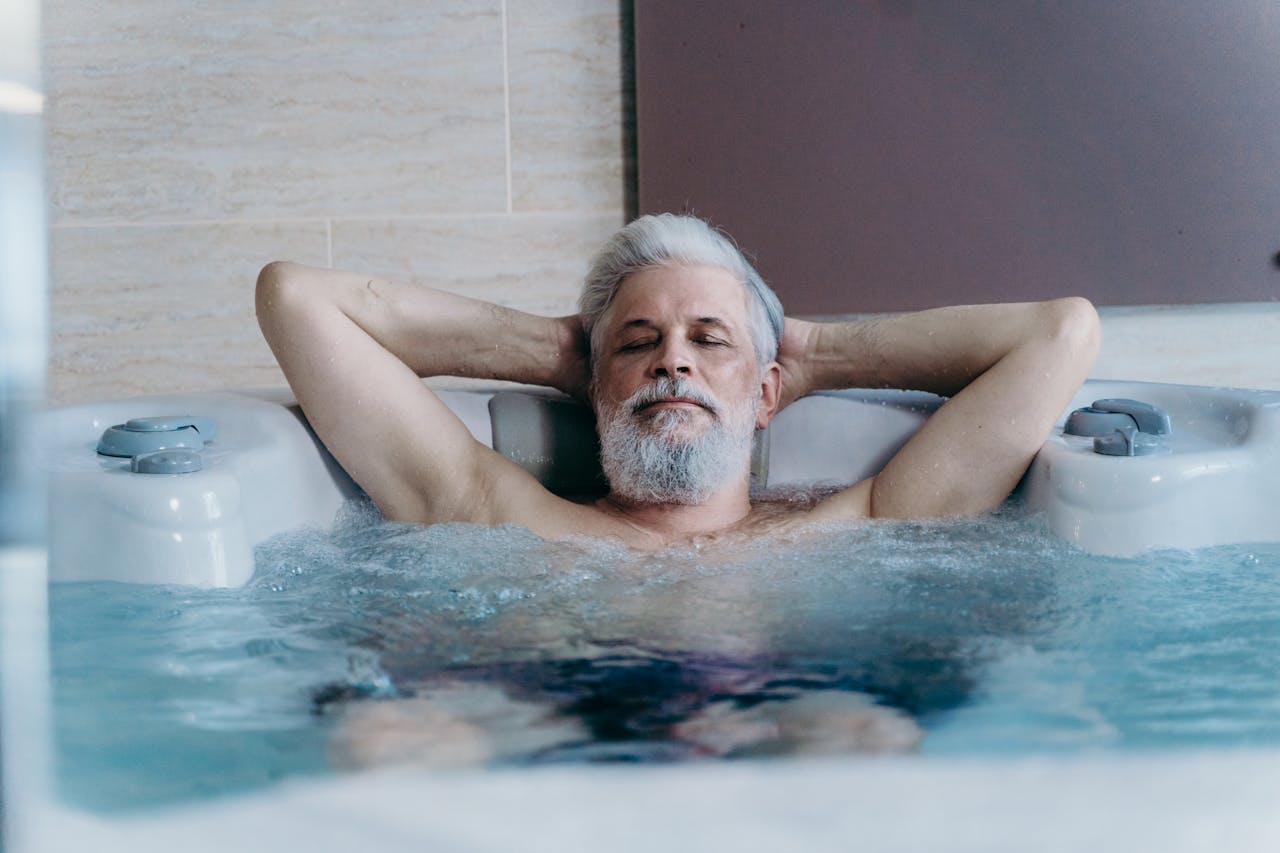 Elderly man with grey hair enjoying relaxation in an indoor jacuzzi.